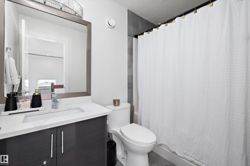 The bathroom features a vanity with a white countertop and a rectangular sink, a framed mirror, and a toilet - 6303 169 Avenue, Edmonton, AB - Indoor Photo Showing Bathroom