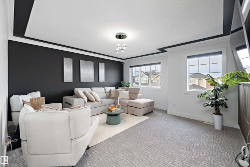 Living room featuring a dark accent wall, light-colored carpet, and two large windows providing natural light - 6303 169 Avenue, Edmonton, AB - Indoor