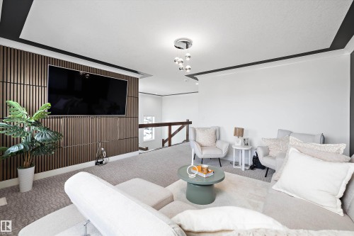 This inviting living area features a decorative wood-paneled wall, a flat-screen display, and carpeting - 6303 169 Avenue, Edmonton, AB - Indoor Photo Showing Living Room
