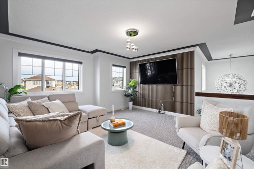 This living area features large windows providing views of the surrounding neighborhood, a ceiling-mounted light fixture, and a decorative accent wall - 6303 169 Avenue, Edmonton, AB - Indoor Photo Showing Living Room