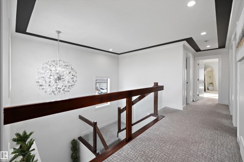 The property features a hallway with a patterned carpet, recessed lighting, and a decorative chandelier - 6303 169 Avenue, Edmonton, AB - Indoor Photo Showing Other Room