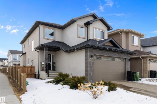 The property features a stucco exterior with decorative stone accents, a dark shingled roof, and an attached garage with a drive - 6303 169 Avenue, Edmonton, AB - Outdoor