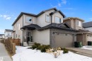 The property features a stucco exterior with decorative stone accents, a dark shingled roof, and an attached garage with a drive - 6303 169 Avenue, Edmonton, AB  - Outdoor 