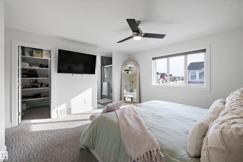 This sleeping area features a ceiling fan, a window providing natural light, and patterned carpeting - 6303 169 Avenue, Edmonton, AB - Indoor Photo Showing Bedroom