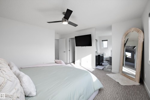 Bedroom space featuring a ceiling fan with integrated lighting, light-colored walls, and patterned carpeting - 6303 169 Avenue, Edmonton, AB - Indoor Photo Showing Bedroom