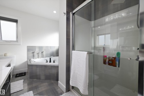 The bathroom features a glass-enclosed shower, a built-in bathtub with tiled surround, and a window providing natural light - 6303 169 Avenue, Edmonton, AB - Indoor Photo Showing Bathroom