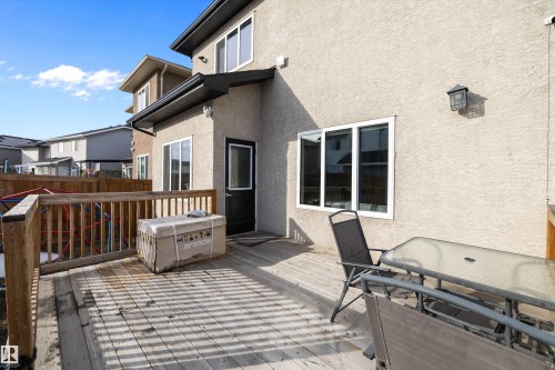 The property features an exterior deck with a wooden railing, a white framed window, and a dark exterior door - 6303 169 Avenue, Edmonton, AB - Outdoor With Deck Patio Veranda With Exterior