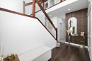 The property features rich hardwood flooring, a staircase with wooden handrails and glass panels, and a modern accent wall with vertical wooden slats - 6303 169 Avenue, Edmonton, AB  - Indoor Photo Showing Other Room 
