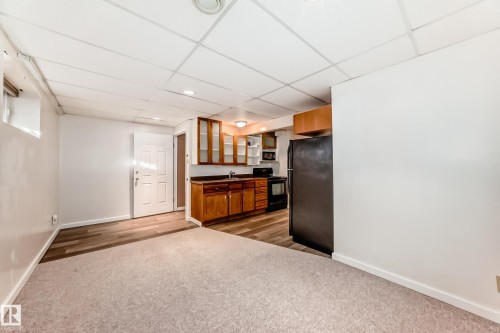Kitchen with brown cabinets, dark countertops, black appliances, light colored carpet, and a drop ceiling - 11609 125 Street, Edmonton, AB - Indoor Photo Showing Other Room