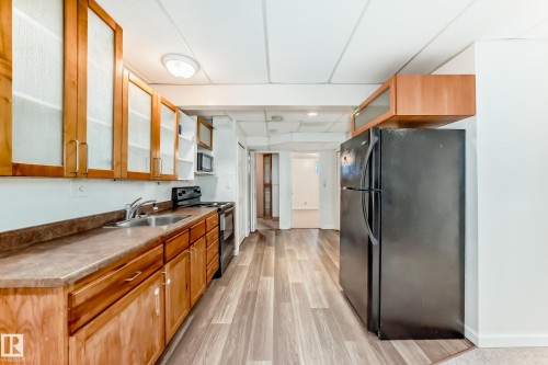 Kitchen with glass insert cabinets, black appliances, brown cabinets, and light wood-style floors - 11609 125 Street, Edmonton, AB - Indoor Photo Showing Other Room