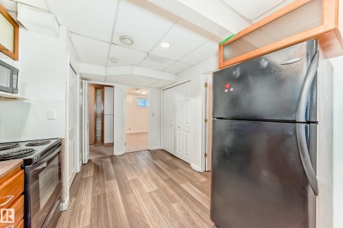 Kitchen with freestanding refrigerator, range with electric stovetop, light wood finished floors, stainless steel microwave, and glass insert cabinets - 11609 125 Street, Edmonton, AB - Indoor Photo Showing Kitchen