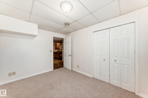 Unfurnished bedroom featuring a drop ceiling, carpet, and a closet - 11609 125 Street, Edmonton, AB - Indoor Photo Showing Other Room