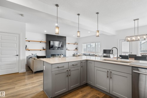 The kitchen features gray cabinetry with brushed nickel hardware, a light-colored countertop, and a stainless steel sink with a modern faucet - 4917 Charles Point(E), Edmonton, AB - Indoor Photo Showing Kitchen With Upgraded Kitchen