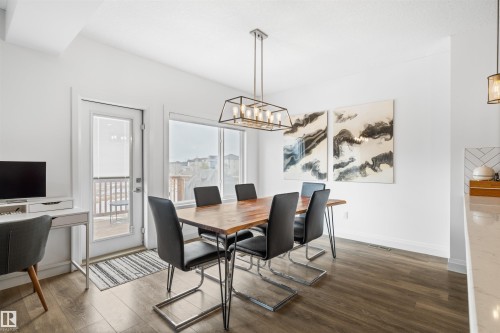 This dining area features wood-look flooring, white walls, and a contemporary linear chandelier - 4917 Charles Point(E), Edmonton, AB - Indoor Photo Showing Dining Room