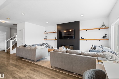 Living area featuring light wood flooring, a fireplace with a black accent wall, and built-in shelving - 4917 Charles Point(E), Edmonton, AB - Indoor Photo Showing Living Room