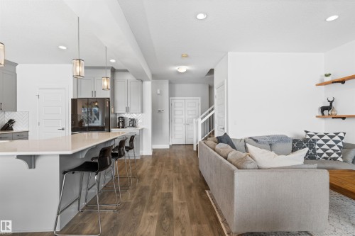 Open concept living area featuring a kitchen island with seating, pendant lighting, and engineered wood flooring - 4917 Charles Point(E), Edmonton, AB - Indoor