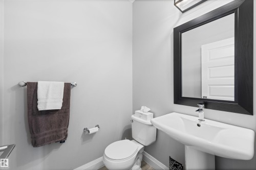 This powder room features a pedestal sink with a modern faucet, a framed mirror, and light gray walls - 4917 Charles Point(E), Edmonton, AB - Indoor Photo Showing Bathroom