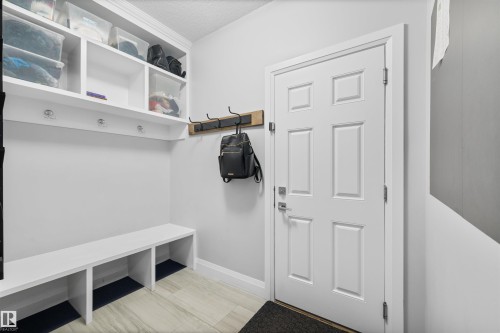 This mudroom features built-in white shelving with hooks, a white bench, and light-colored flooring - 4917 Charles Point(E), Edmonton, AB - Indoor Photo Showing Other Room