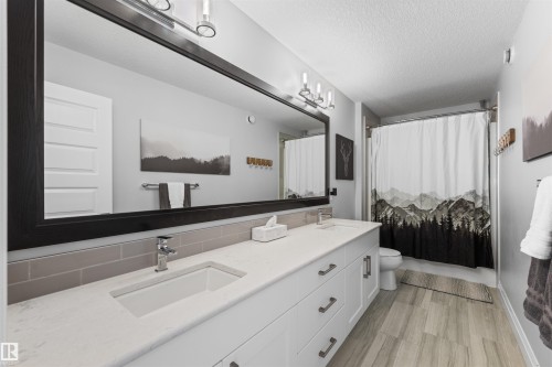 This bathroom features a double vanity with a light-colored countertop and white cabinetry - 4917 Charles Point(E), Edmonton, AB - Indoor Photo Showing Bathroom