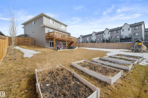 The property features a spacious yard with a deck and built-in garden beds - 4917 Charles Point(E), Edmonton, AB - Outdoor With Deck Patio Veranda