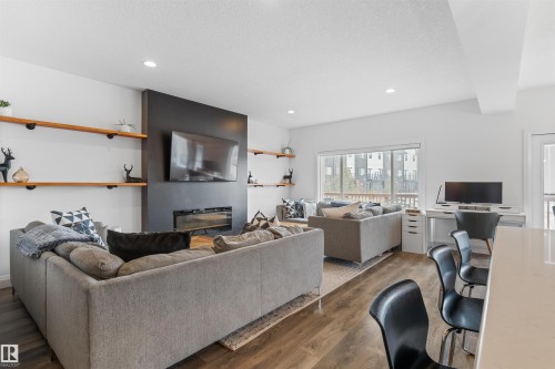 This living space features wood-style flooring, white walls, and recessed lighting - 4917 Charles Point(E), Edmonton, AB - Indoor Photo Showing Living Room With Fireplace