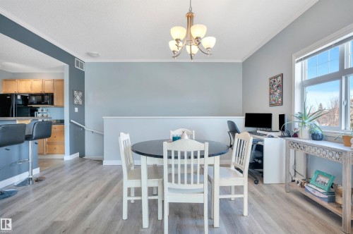 Dining area featuring light-toned flooring, a window providing natural light, and a chandelier - 106 3040 Spence Wynd, Edmonton, AB - Indoor Photo Showing Dining Room