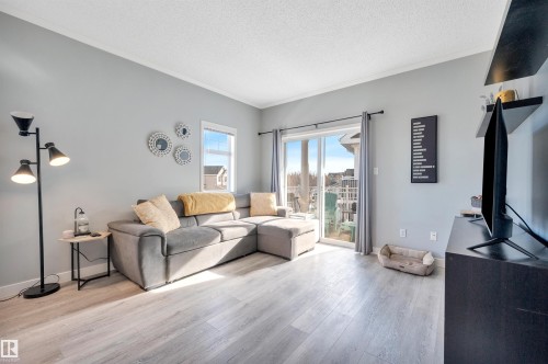 The living area features light-toned flooring, a light gray wall color, and a sliding glass door providing external views - 106 3040 Spence Wynd, Edmonton, AB - Indoor Photo Showing Living Room