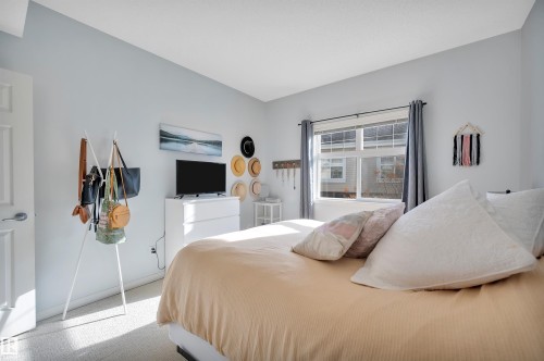 Bedroom featuring light blue walls, carpeted floors, and a window with blinds and curtains - 106 3040 Spence Wynd, Edmonton, AB - Indoor Photo Showing Bedroom