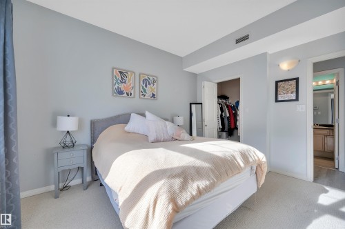 This bedroom features light gray walls, light-colored carpeting, and a built-in wall niche with a light fixture - 106 3040 Spence Wynd, Edmonton, AB - Indoor Photo Showing Bedroom