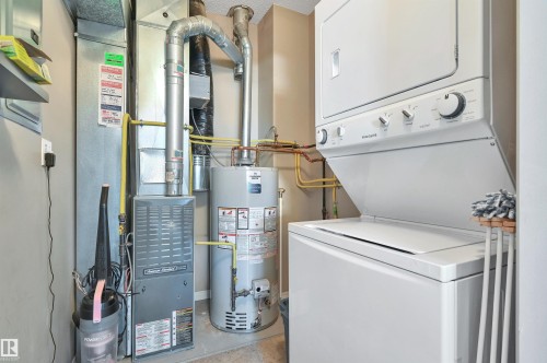 Laundry area with a stacked washer and dryer, water heater, and furnace - 106 3040 Spence Wynd, Edmonton, AB - Indoor Photo Showing Laundry Room