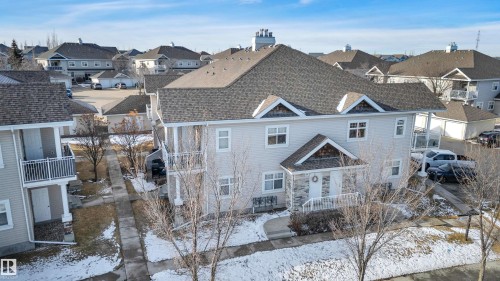 The property features a multi-level building with light-colored siding and a dark shingled roof - 106 3040 Spence Wynd, Edmonton, AB - Outdoor With Facade