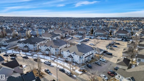 Aerial view of the property and surrounding neighbourhood, featuring residential buildings with dark roofs and light-colored siding - 106 3040 Spence Wynd, Edmonton, AB - Outdoor With View