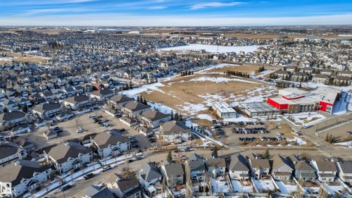 Expansive aerial view of the neighborhood, showcasing numerous residential properties with diverse architectural styles, open land, and a community building with a red roof - 106 3040 Spence Wynd, Edmonton, AB - Outdoor With View