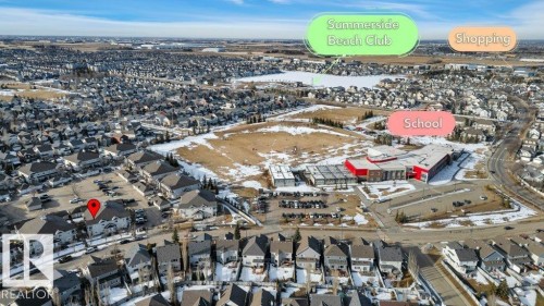 Aerial view of the community, highlighting its proximity to a large body of water, a prominent school building, and commercial areas - 106 3040 Spence Wynd, Edmonton, AB - Outdoor With View