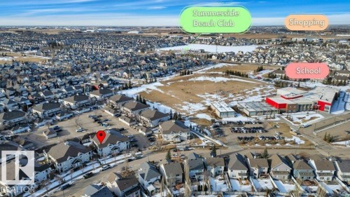 Aerial view showcasing the property's location within a residential neighborhood, with nearby community amenities including a school building and a shopping area - 106 3040 Spence Wynd, Edmonton, AB - Outdoor With View