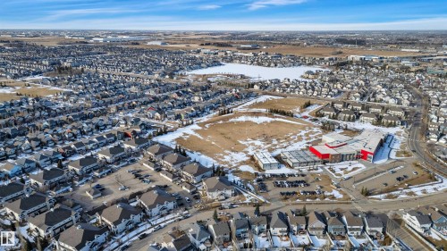 Aerial view of the surrounding neighbourhood, featuring residential properties, a central body of water, and a commercial area - 106 3040 Spence Wynd, Edmonton, AB - Outdoor With View