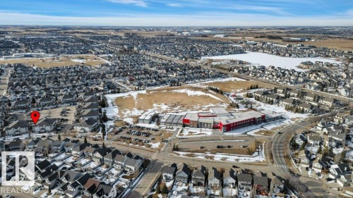 Aerial view of the surrounding neighborhood, featuring residential properties, a building with a red roof, and a large body of water - 106 3040 Spence Wynd, Edmonton, AB - Outdoor With View