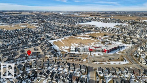 Aerial view of the property's location within a developed neighborhood, featuring many residential buildings and a body of water in the distance - 106 3040 Spence Wynd, Edmonton, AB - Outdoor With View