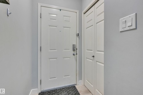 The property features a white paneled door with a contemporary handle set, accompanied by a spacious storage closet - 106 3040 Spence Wynd, Edmonton, AB - Indoor Photo Showing Other Room