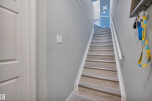 The property features a staircase with light wood-style treads and white risers, complemented by a white handrail - 106 3040 Spence Wynd, Edmonton, AB - Indoor Photo Showing Other Room