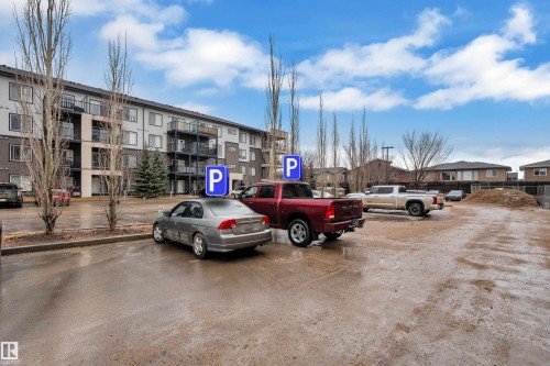 The property features a parking area with marked parking spaces - 128 390 Windermere Road, Edmonton, AB - Outdoor