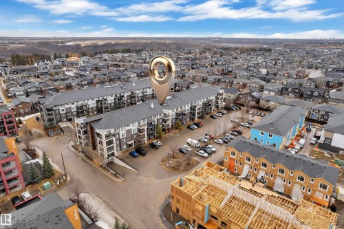 Aerial view of the property and its surrounding development, featuring a multi-story building with balconies and a parking area - 128 390 Windermere Road, Edmonton, AB - Outdoor With View