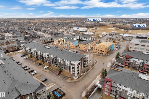 The property is located within a developed community featuring various residential buildings and parking areas - 128 390 Windermere Road, Edmonton, AB - Outdoor With View