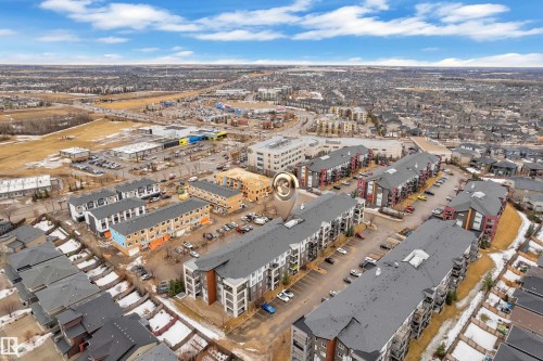Aerial view showcasing the property's location within a developed community, featuring residential buildings and nearby commercial areas - 128 390 Windermere Road, Edmonton, AB - Outdoor With View