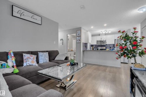 This inviting living area features hardwood flooring and light gray walls, offering a versatile backdrop - 128 390 Windermere Road, Edmonton, AB - Indoor