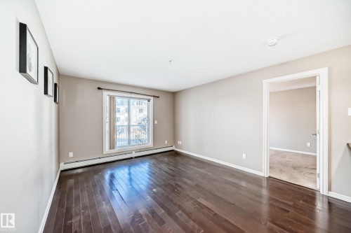 This room features dark hardwood flooring, light-colored walls, and a window with a balcony view - 208 2204 44 Ave, Edmonton, AB - Indoor Photo Showing Other Room