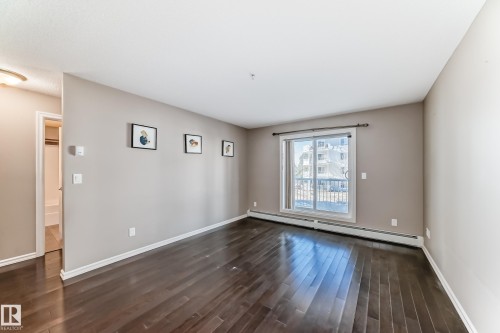 This inviting room features rich dark wood flooring and light-toned walls, creating a warm ambiance - 208 2204 44 Ave, Edmonton, AB - Indoor Photo Showing Other Room