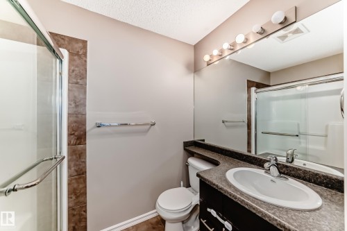 Bathroom featuring a glass-enclosed shower, a vanity with a sink and faucet, a large mirror with overhead lighting, and tiled flooring - 208 2204 44 Ave, Edmonton, AB - Indoor Photo Showing Bathroom