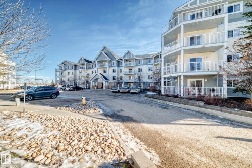 The property features a multi-story building with a light-colored facade and white railings on the balconies - 208 2204 44 Ave, Edmonton, AB - Outdoor With Balcony With Facade