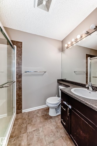 Bathroom featuring a glass-enclosed shower, a vanity with a dark countertop and integrated sink, and large wall-mounted mirror - 208 2204 44 Ave, Edmonton, AB - Indoor Photo Showing Bathroom